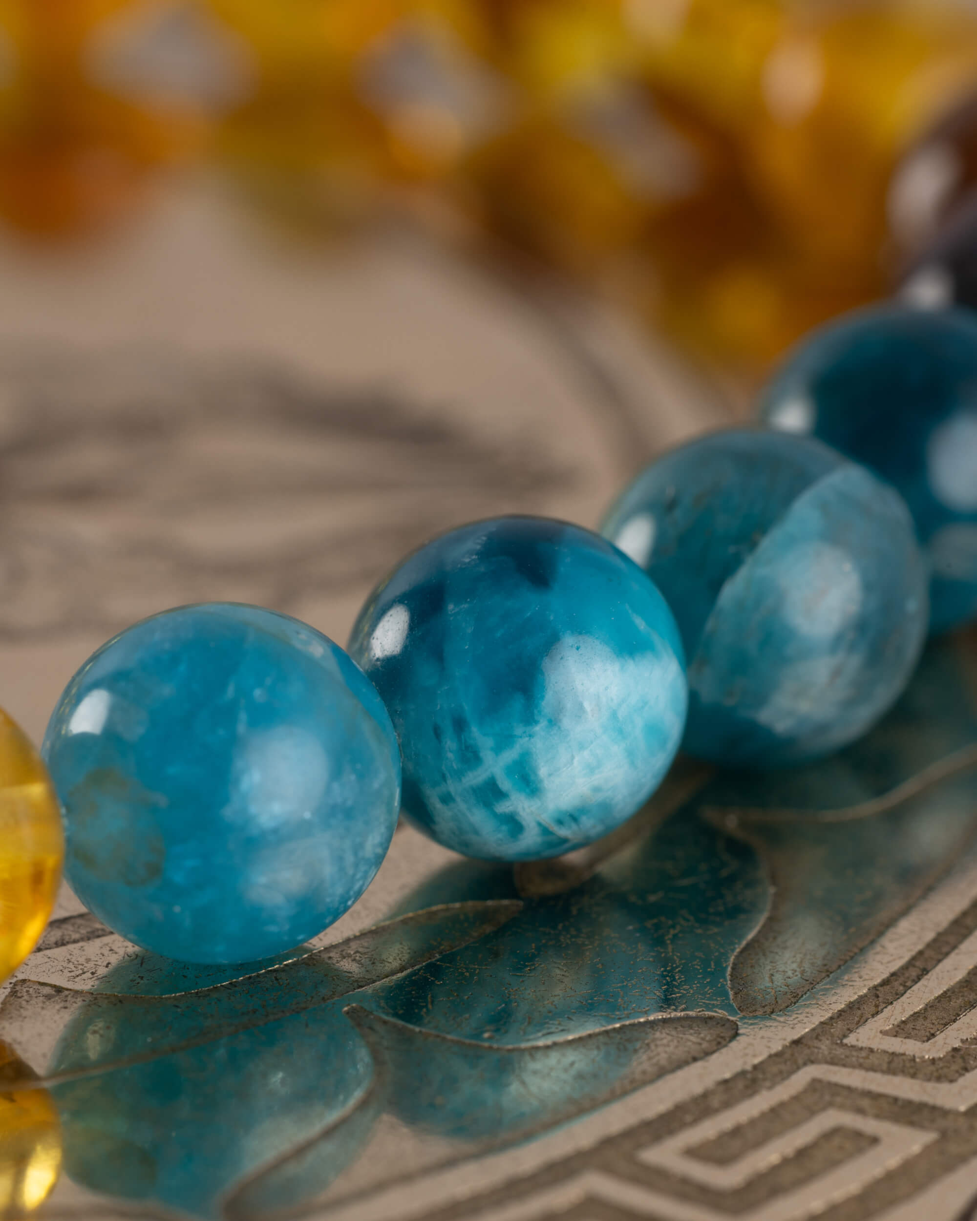 Detalle macro de las cuentas facetadas de Apatita Azul sobre superficie grabada