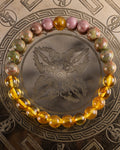 Pulsera Dazbog de 8 mm en Jaspe Unakita, Rodonita y Ámbar, pieza completa sobre placa grabada