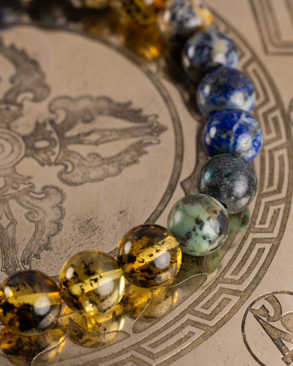 Detalle macro de las cuentas de Lapislázuli y Ámbar de la Pulsera Utu sobre placa grabada