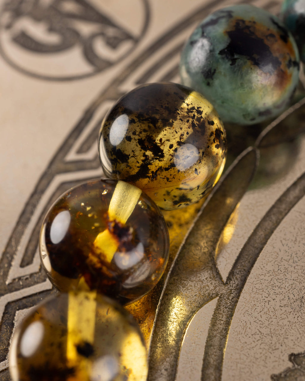 Detalle macro de las cuentas de Ámbar y Turquesa Africana de la Pulsera Utu sobre placa grabada
