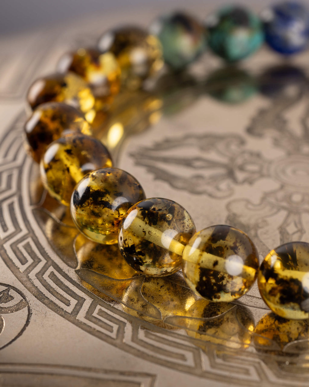 Detalle macro de las cuentas de Ámbar de la Pulsera Utu sobre placa grabada