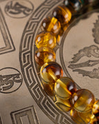 Detalle macro de las cuentas de Ámbar y Ojo de Tigre de la Pulsera Freyr sobre placa grabada