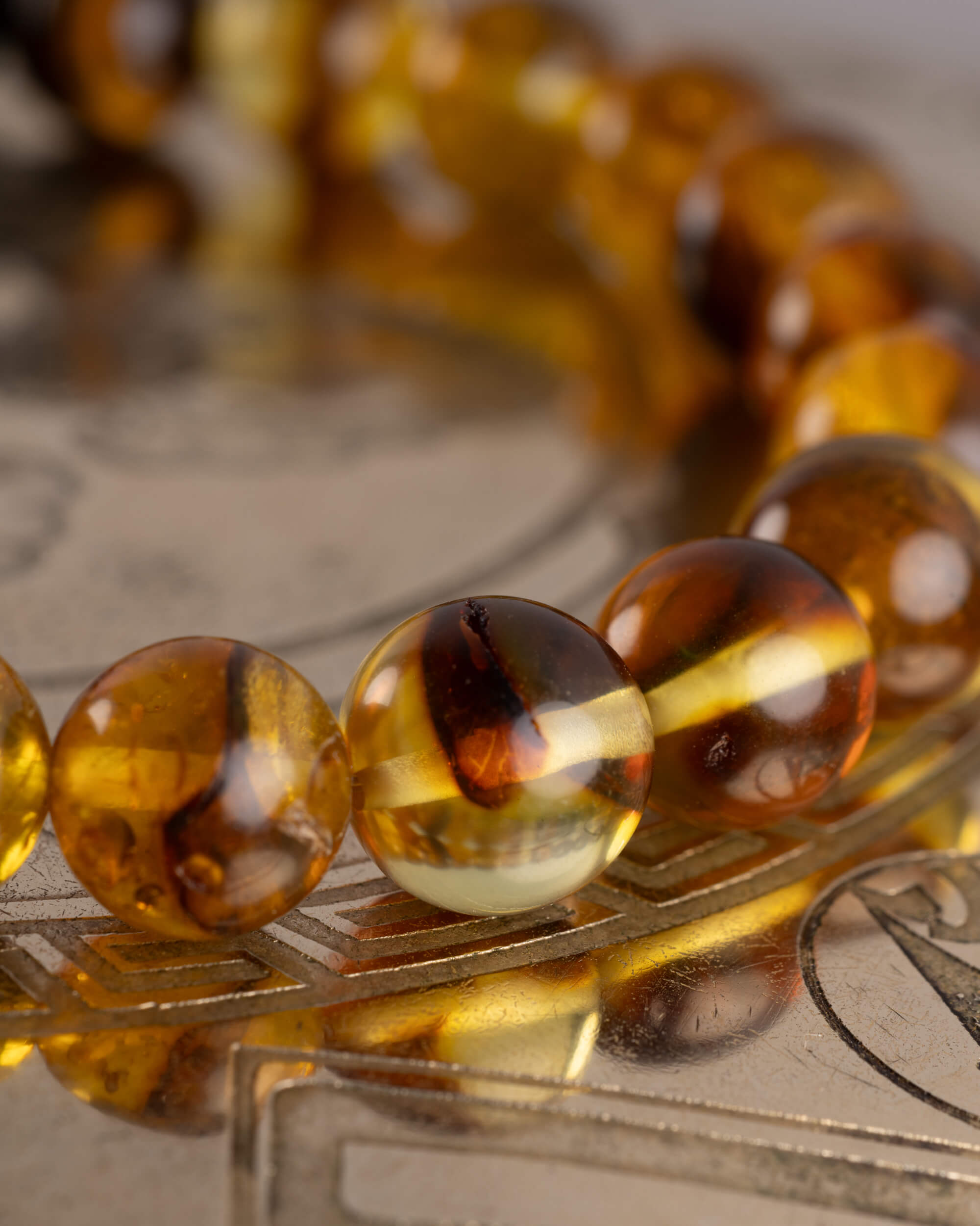 Detalle macro de las cuentas de Ámbar de la Pulsera Freyr sobre placa grabada