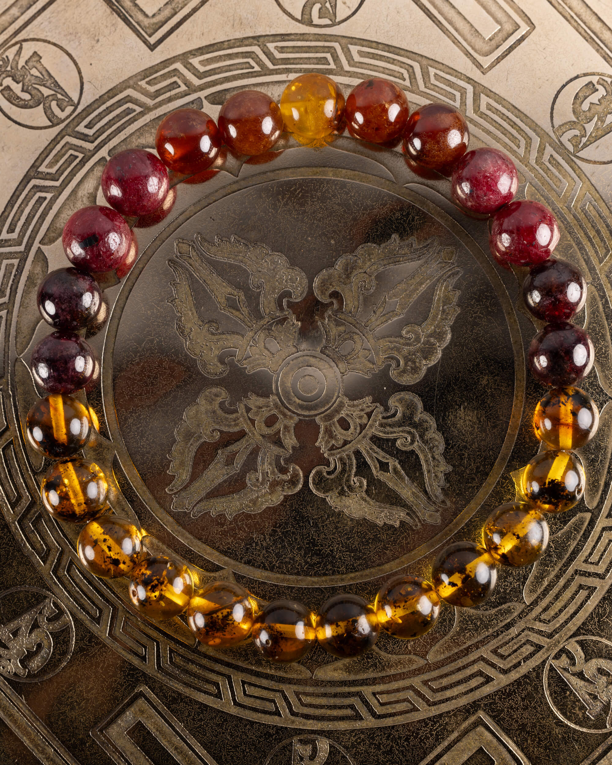 Pulsera Inti de 8 mm en tonos granate y Ámbar, pieza completa sobre placa grabada