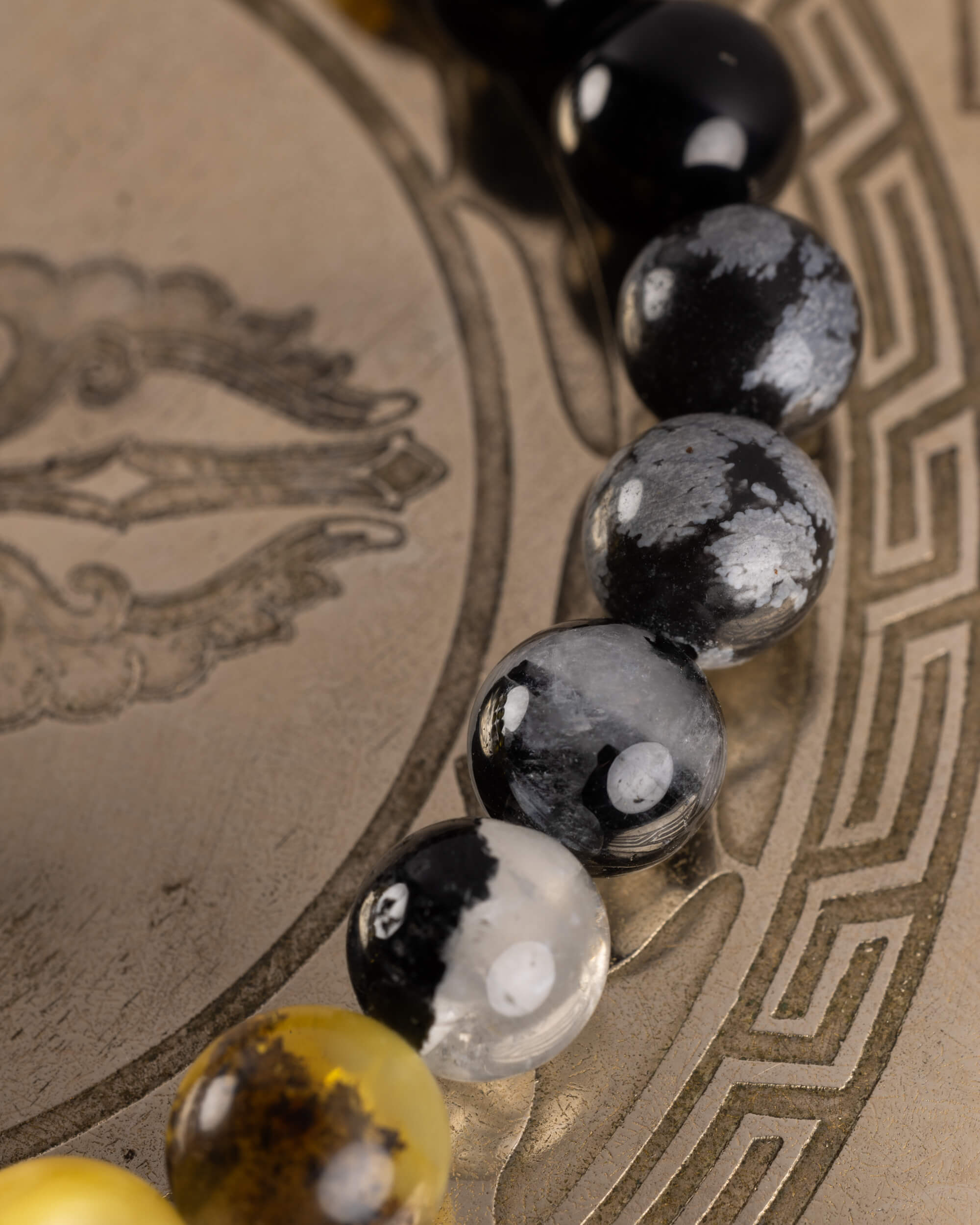 Detalle macro de la transicion entre Obsidiana Copo de Nieve y una cuenta de tono ámbar de la pulsera Horus