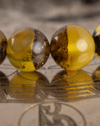 Detalle macro de cuentas de Ámbar con vetas oscuras, pulsera Horus