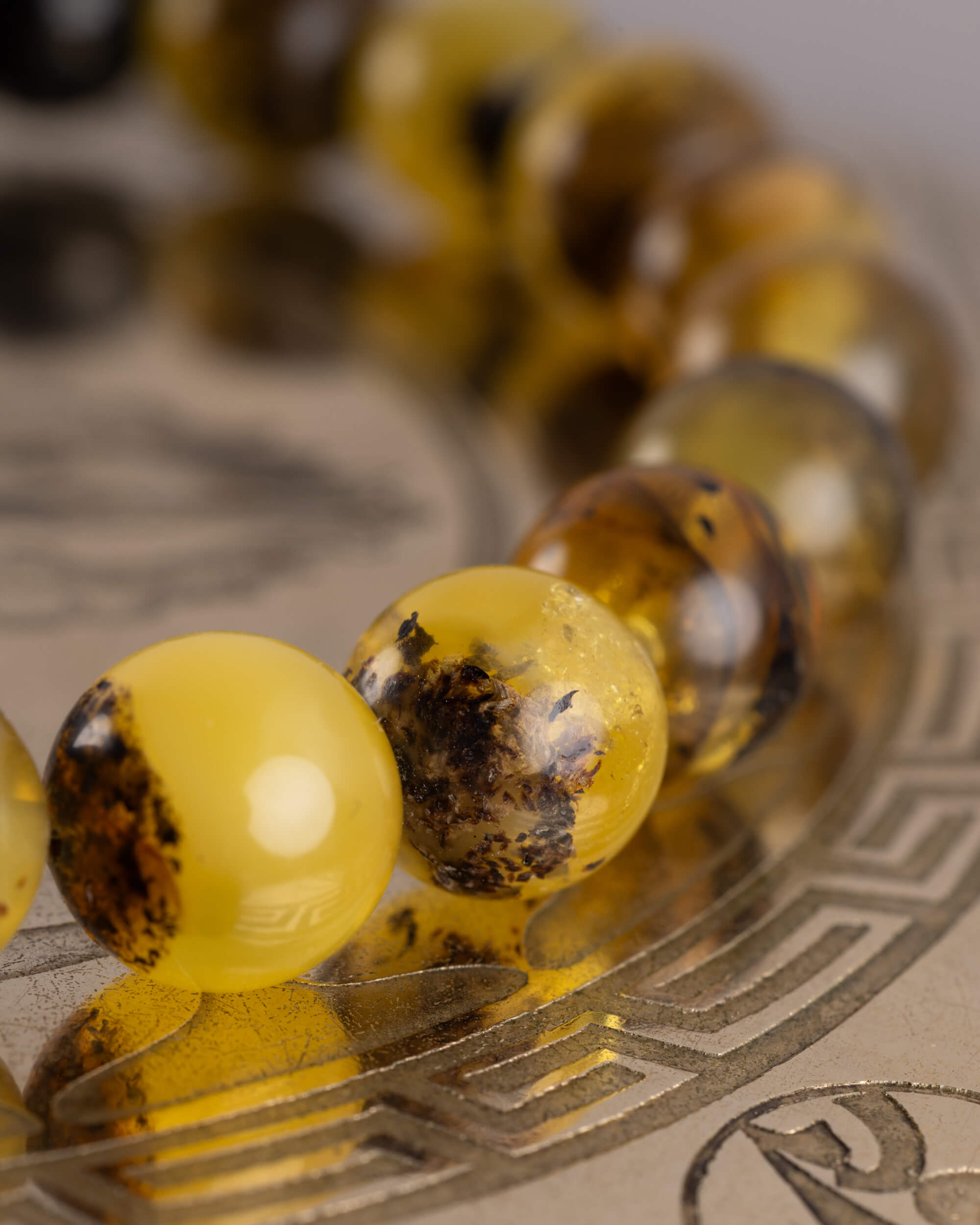 Detalle macro de tres cuentas de Ámbar en tonos dorados y miel, pulsera Horus