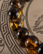 Detalle macro de cuentas de Ámbar y Obsidiana Caoba, pulsera Kinich Ahau