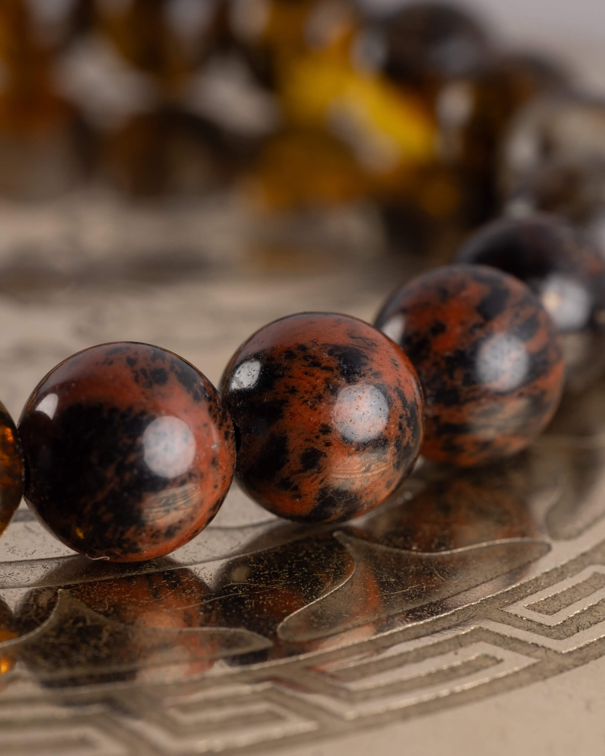 Detalle macro de cuentas de Obsidiana Caoba con veta rojiza y negra