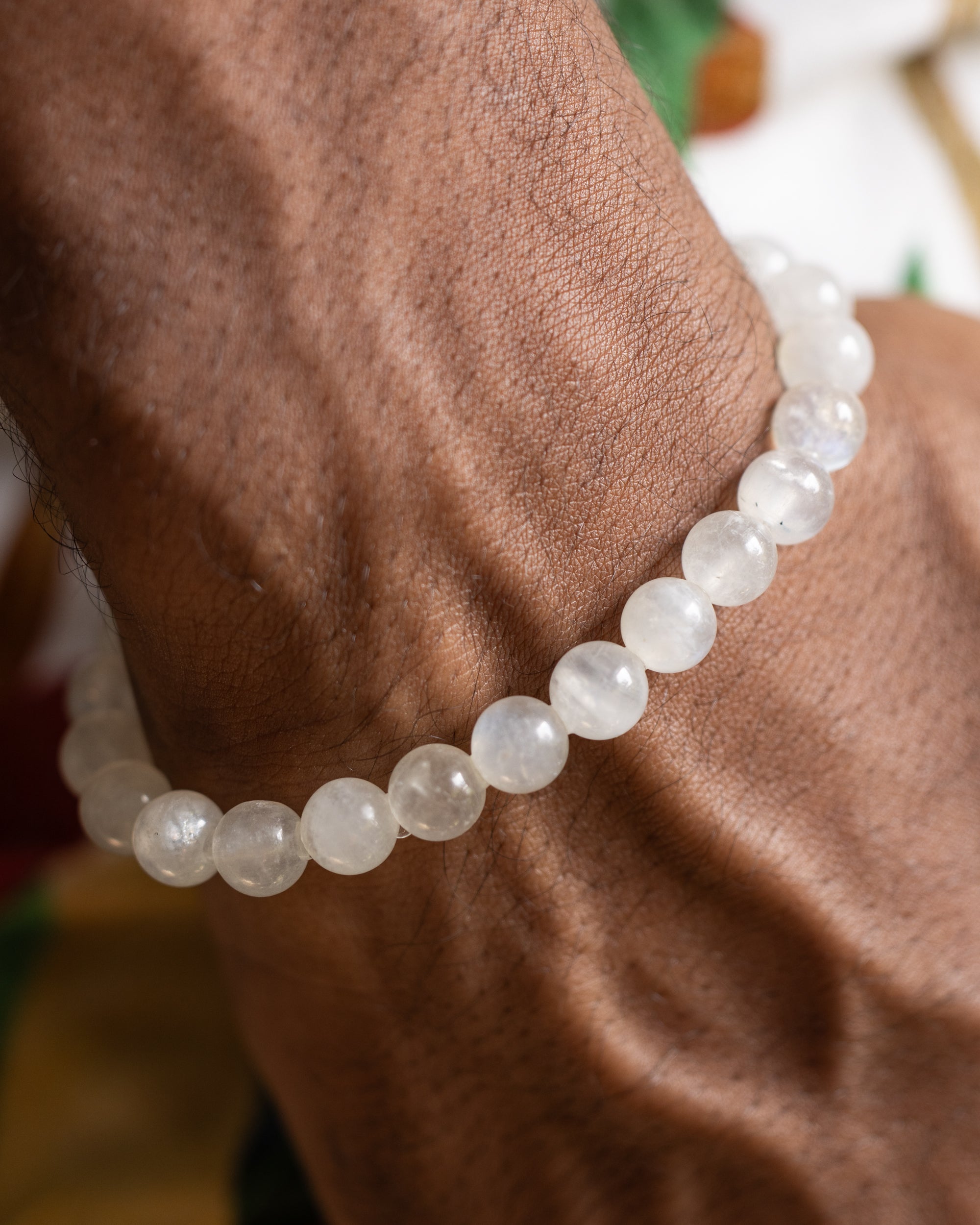 Pulsera de Piedra Luna puesta en la muñeca, cuentas blancas sobre piel