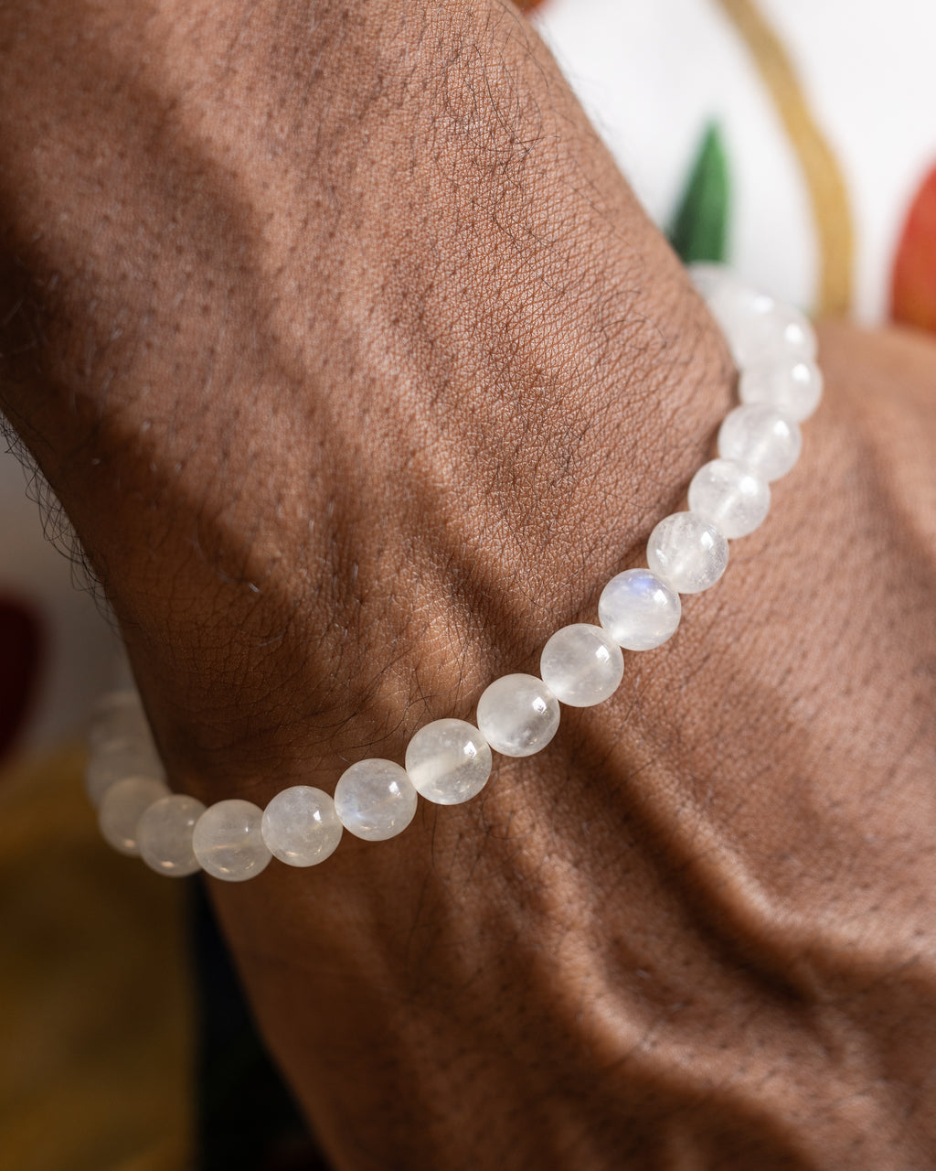 Pulsera de la Piedra Luna puesta en la muñeca, brazo doblado sobre estampado floral