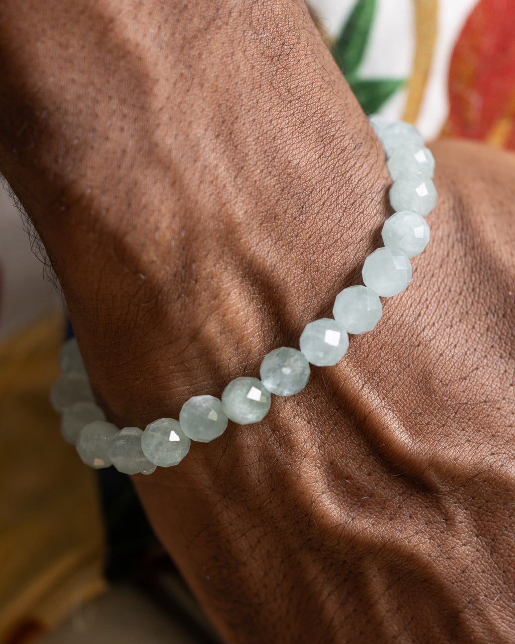 Pulsera de Aguamarina puesta en la muñeca, brazo apoyado sobre tela floral