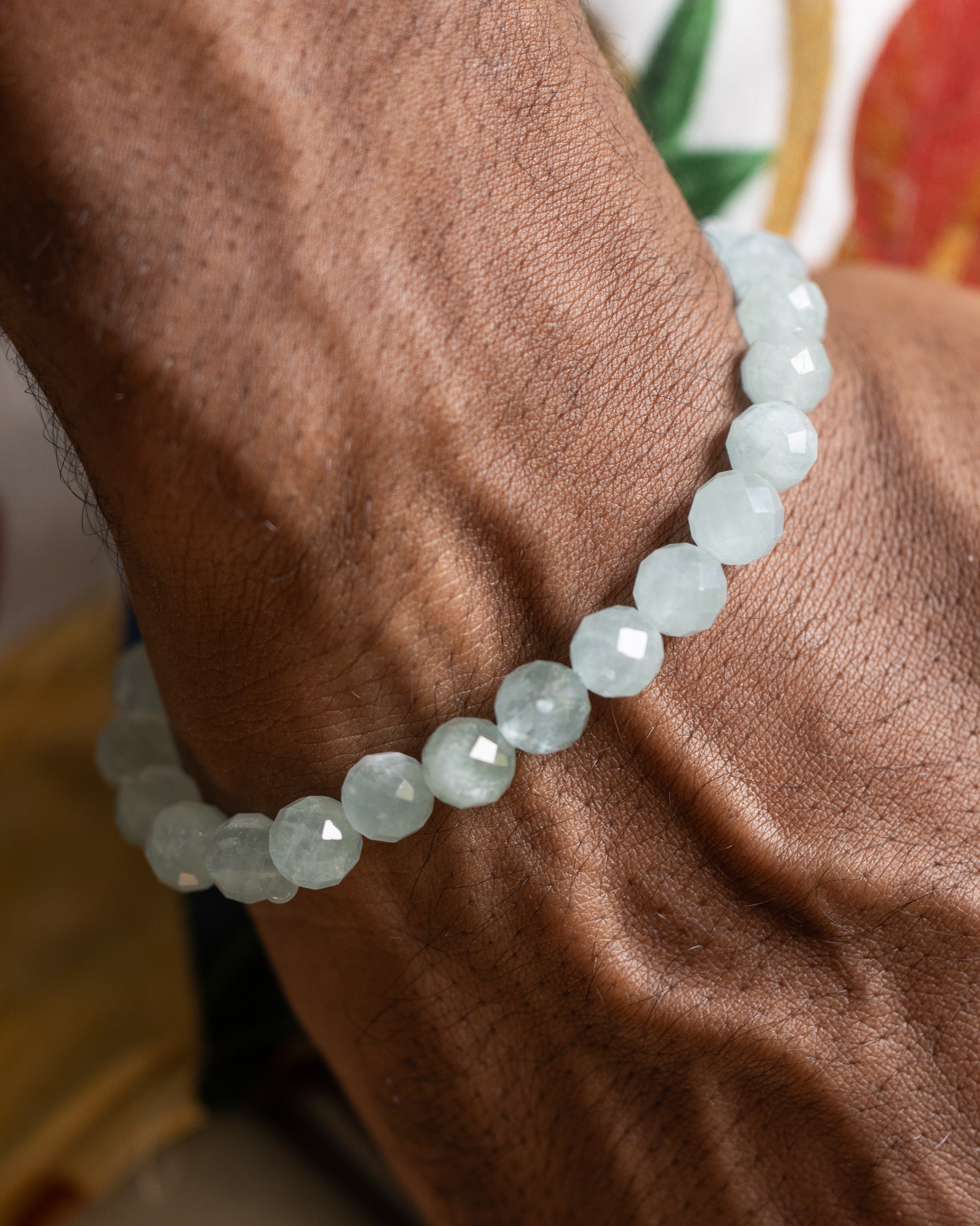 Pulsera de Aguamarina puesta en la muñeca, brazo apoyado sobre tela floral