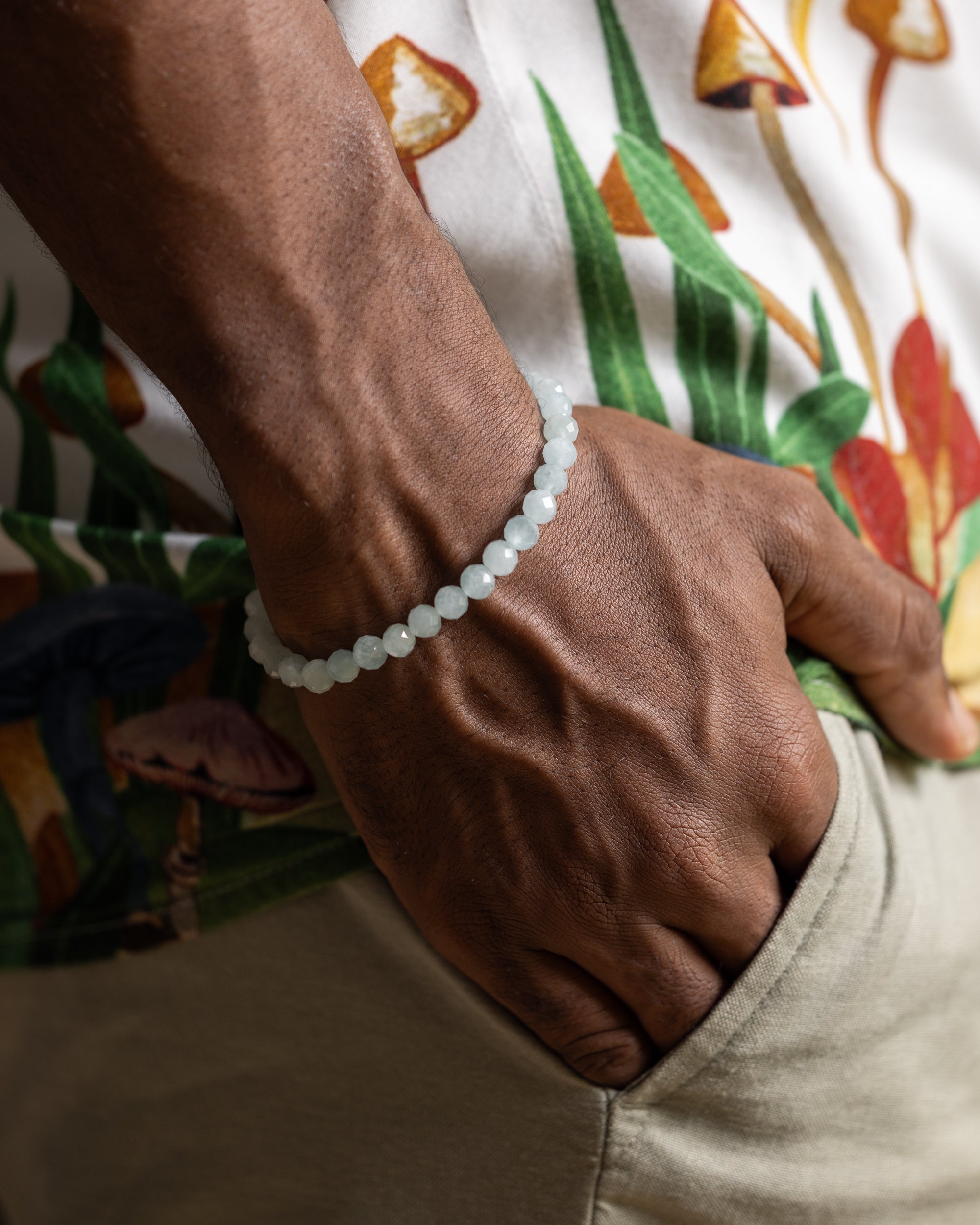 Pulsera de Aguamarina facetada puesta en la muñeca, con camisa estampada de fondo