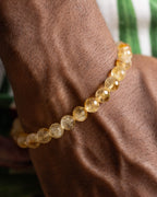 Pulsera de Citrino puesta en la muñeca, brillo dorado de las cuentas facetadas