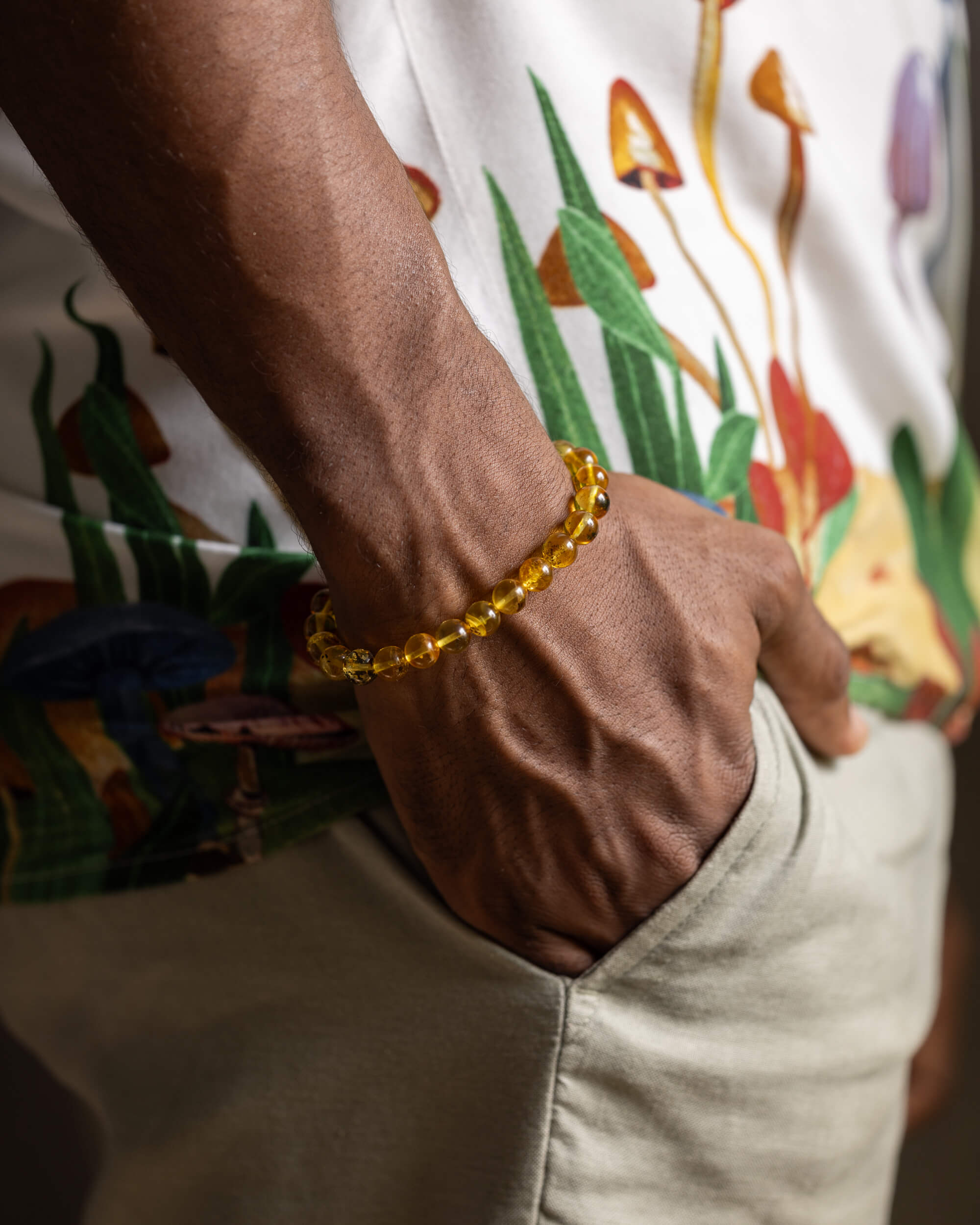 Pulsera de Ámbar puesta en la muñeca sobre pantalón caqui y camisa floral