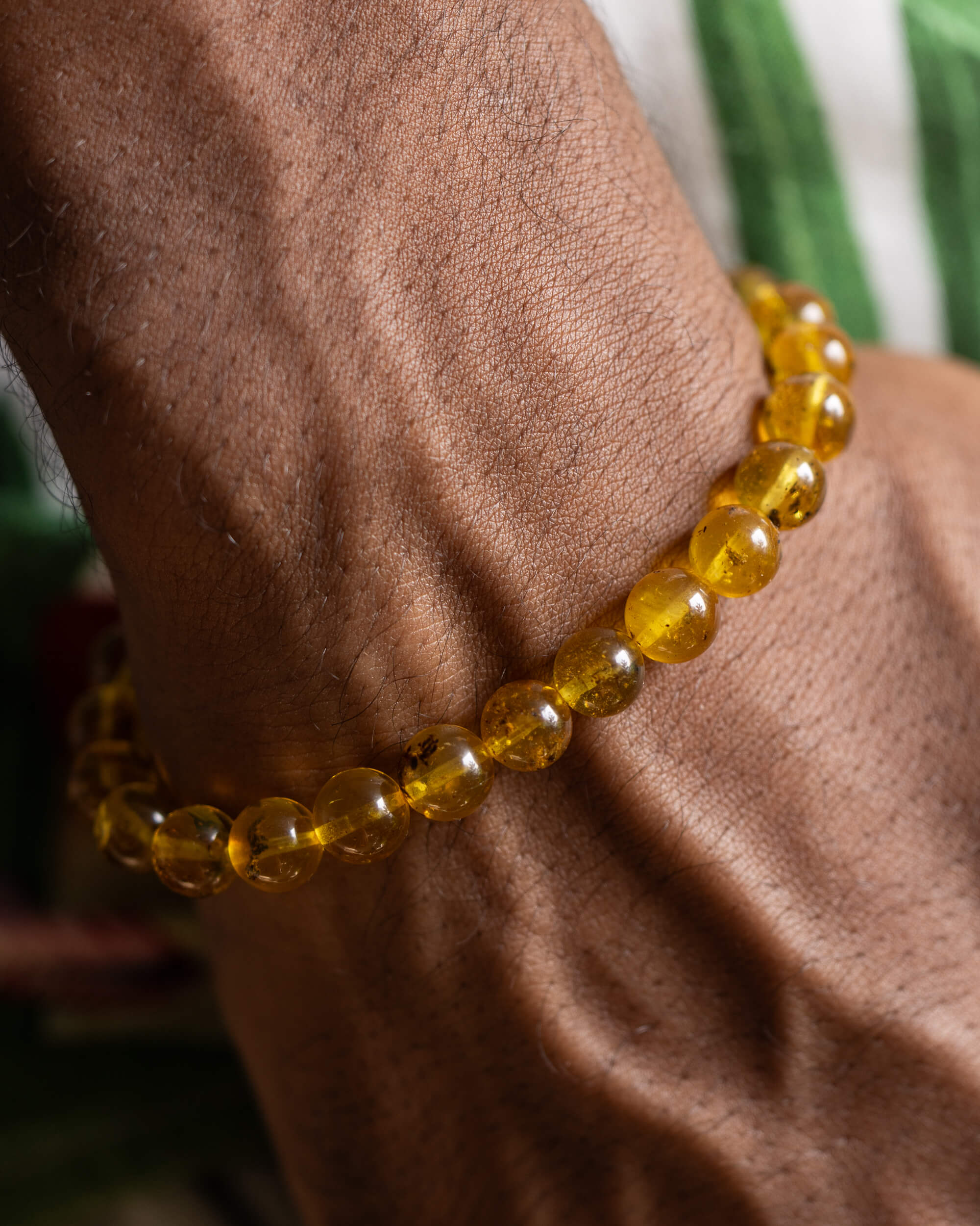 Pulsera de Ámbar puesta en la muñeca, cuentas doradas translúcidas a la luz