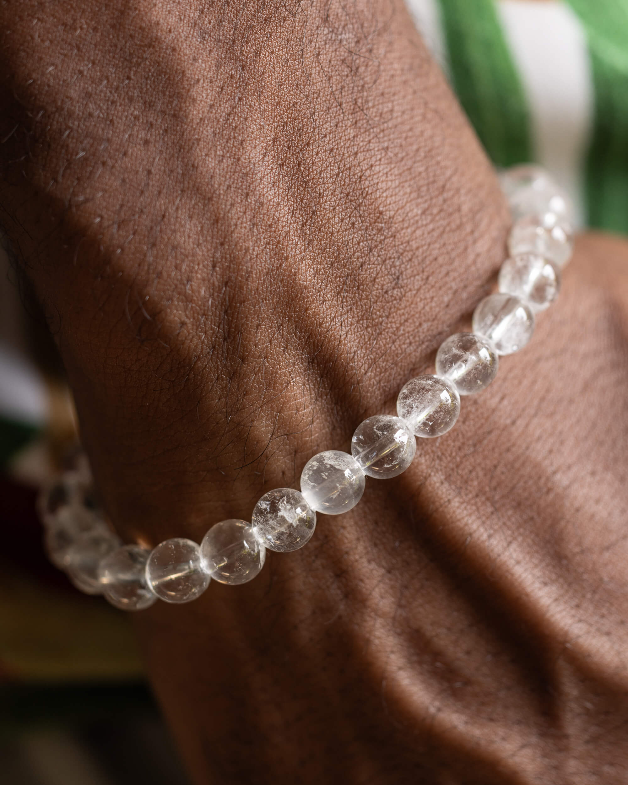 Pulsera de Cuarzo Transparente puesta en la muñeca junto a tela verde