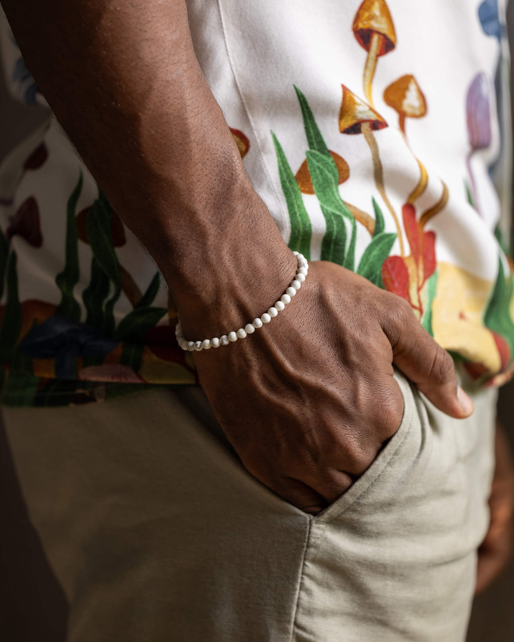 Pulsera de Howlita puesta en la muñeca, mano en el bolsillo de un pantalón