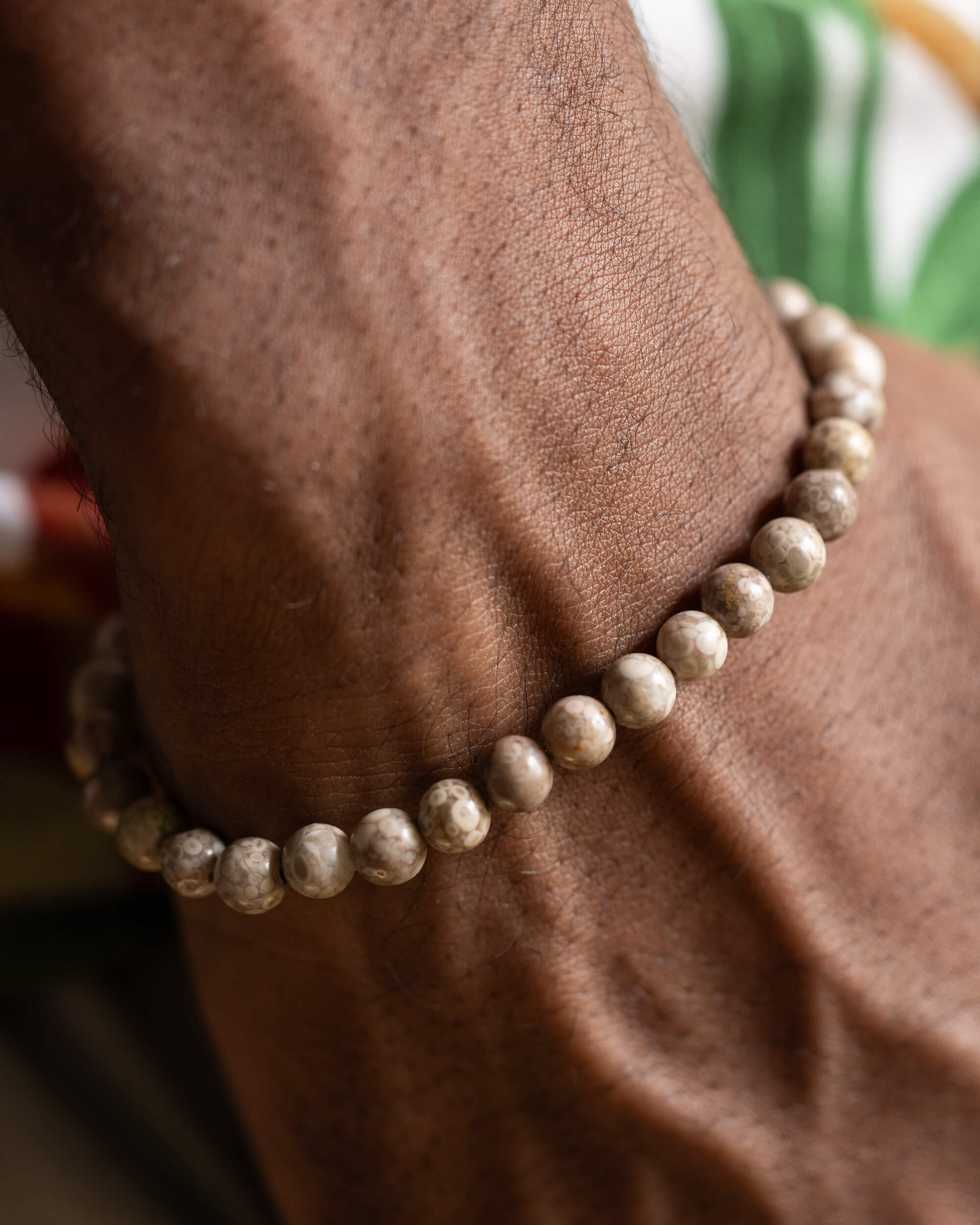Pulsera de Maifanita puesta en la muñeca, textura moteada de las cuentas