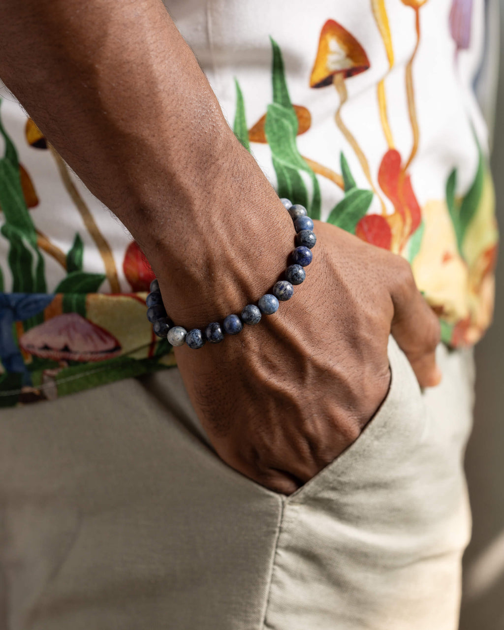 Pulsera de Dumortierita puesta en la muñeca, con camisa estampada de hongos