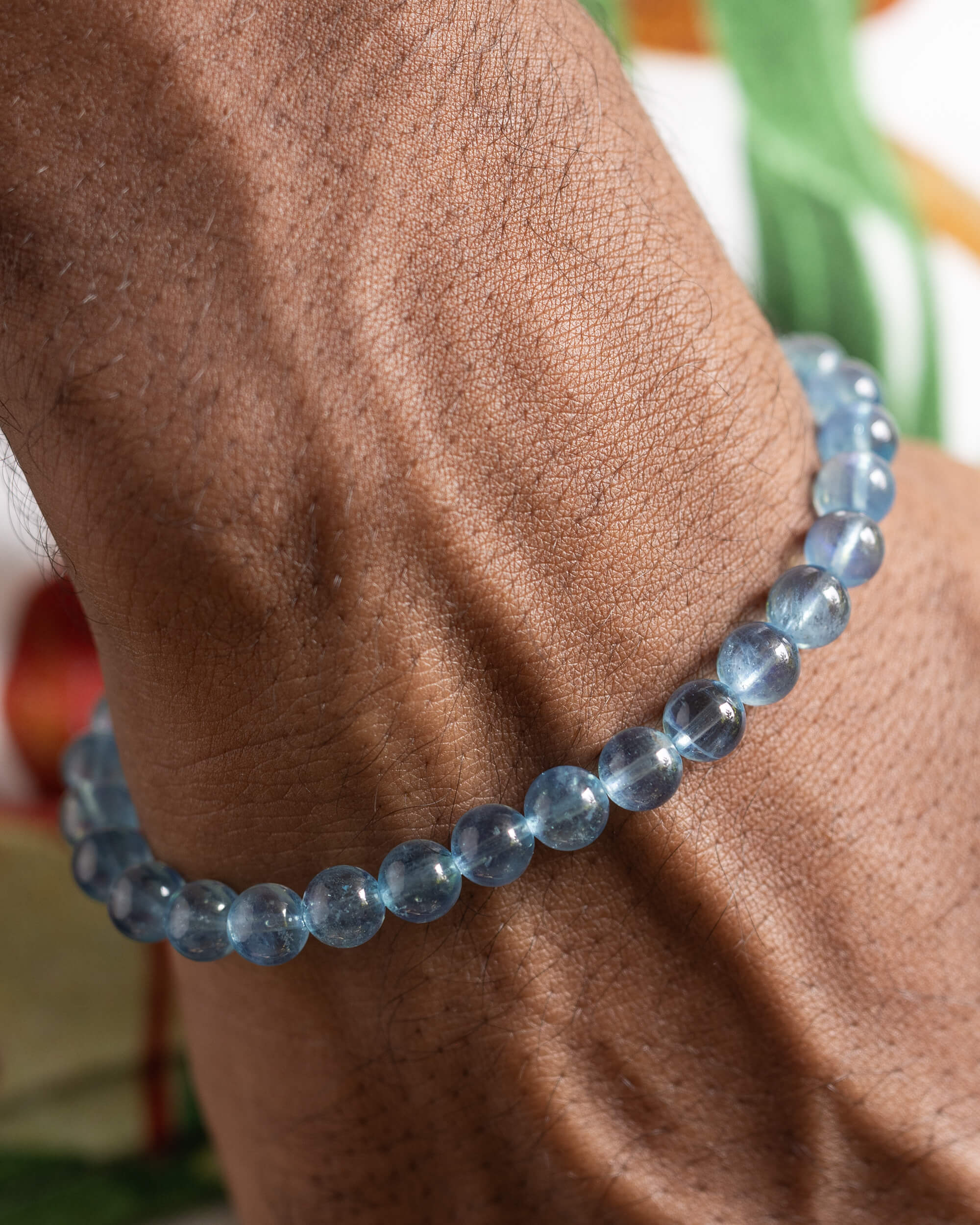 Pulsera de Aguamarina puesta en la muñeca, acercamiento con fondo de hojas verdes