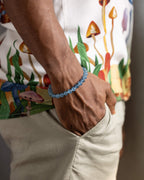 Pulsera de Aguamarina puesta en la muñeca, mano en el bolsillo con camisa estampada