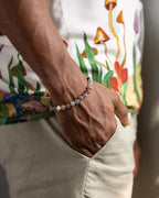 Pulsera de Ágata Botsuana puesta en muñeca, con estampado floral de fondo