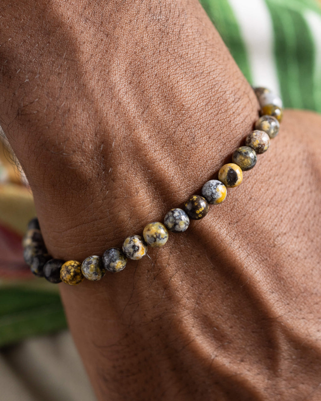 Pulsera de Jaspe Oceánico Amarillo puesta en la muñeca, acercamiento con fondo verde