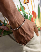 Pulsera de Turmalina Rubelita puesta en la muñeca, mano en el bolsillo con camisa estampada