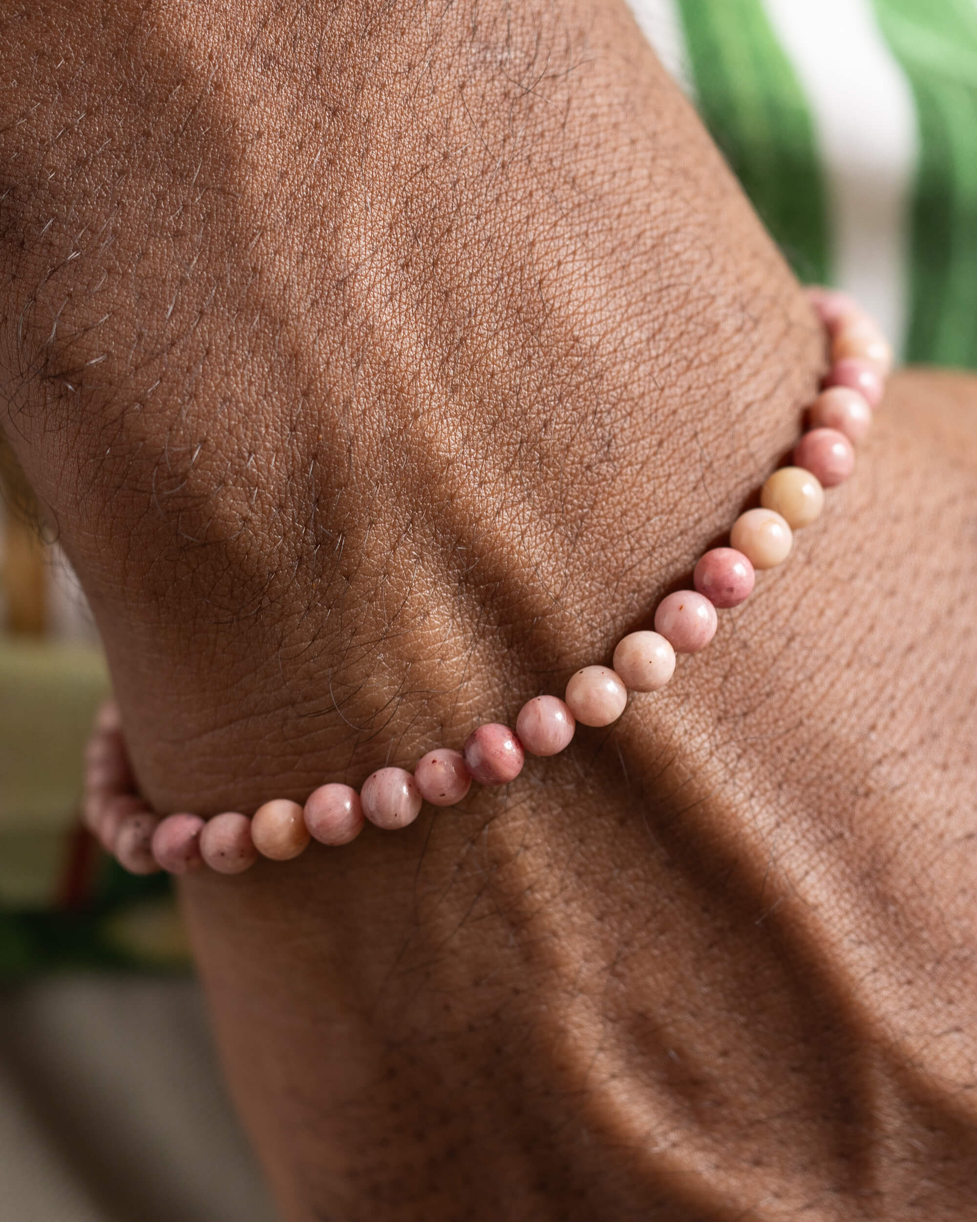 Pulsera de Rodonita Rosa puesta en la muñeca, vista cercana de las cuentas rosas