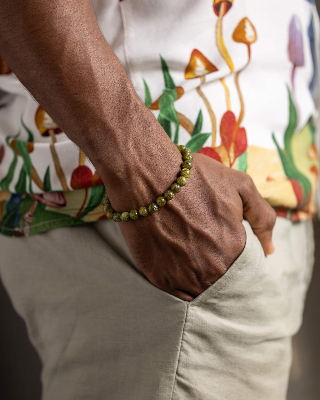 Pulsera de Peridoto puesta en la muñeca, con camisa de estampado de hongos