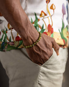 Pulsera de Peridoto puesta en la muñeca, con camisa de estampado de hongos