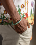 Pulsera de Turquesa Peruana puesta en la muñeca, con camisa de estampado de hongos
