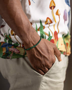 Pulsera de Malaquita puesta en la muñeca, mano dentro del bolsillo de un pantalón claro