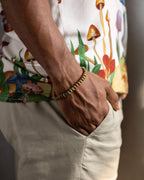 Pulsera de Jaspe Unakita puesta en la muñeca, con camisa de estampado de hongos