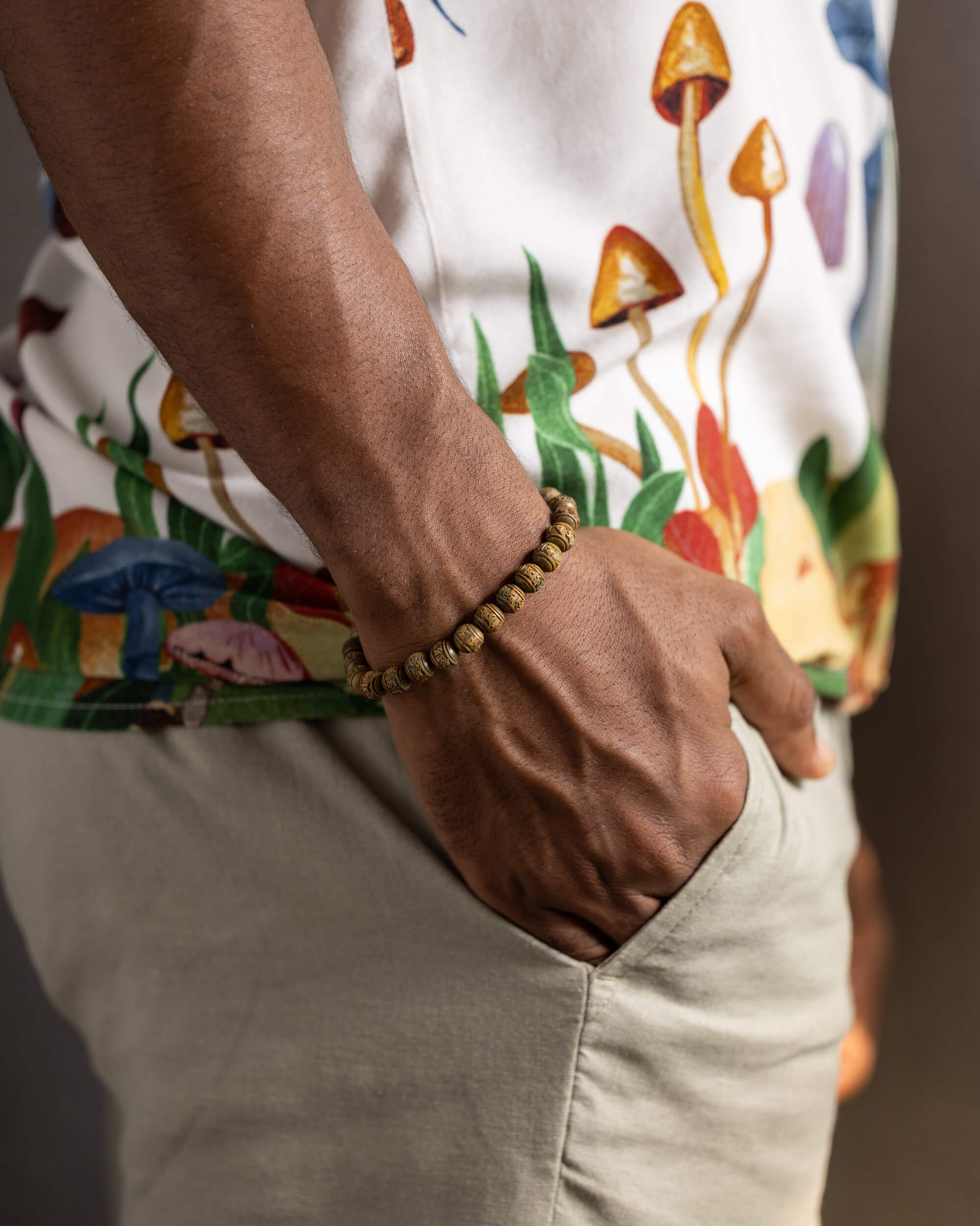 Pulsera de Madera de Sándalo tallada puesta en la muñeca, con camisa estampada de hongos