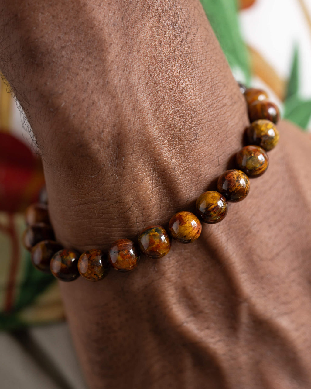 Pulsera de Pietersita puesta en la muñeca sobre fondo con hojas