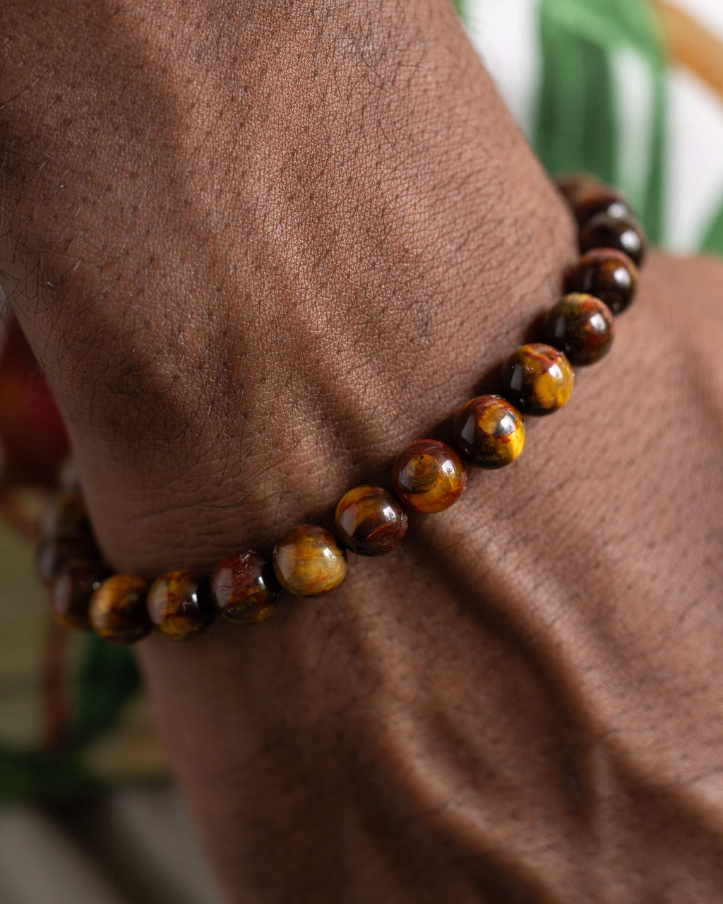 Pulsera de Pietersita puesta en la muñeca sobre fondo con hojas