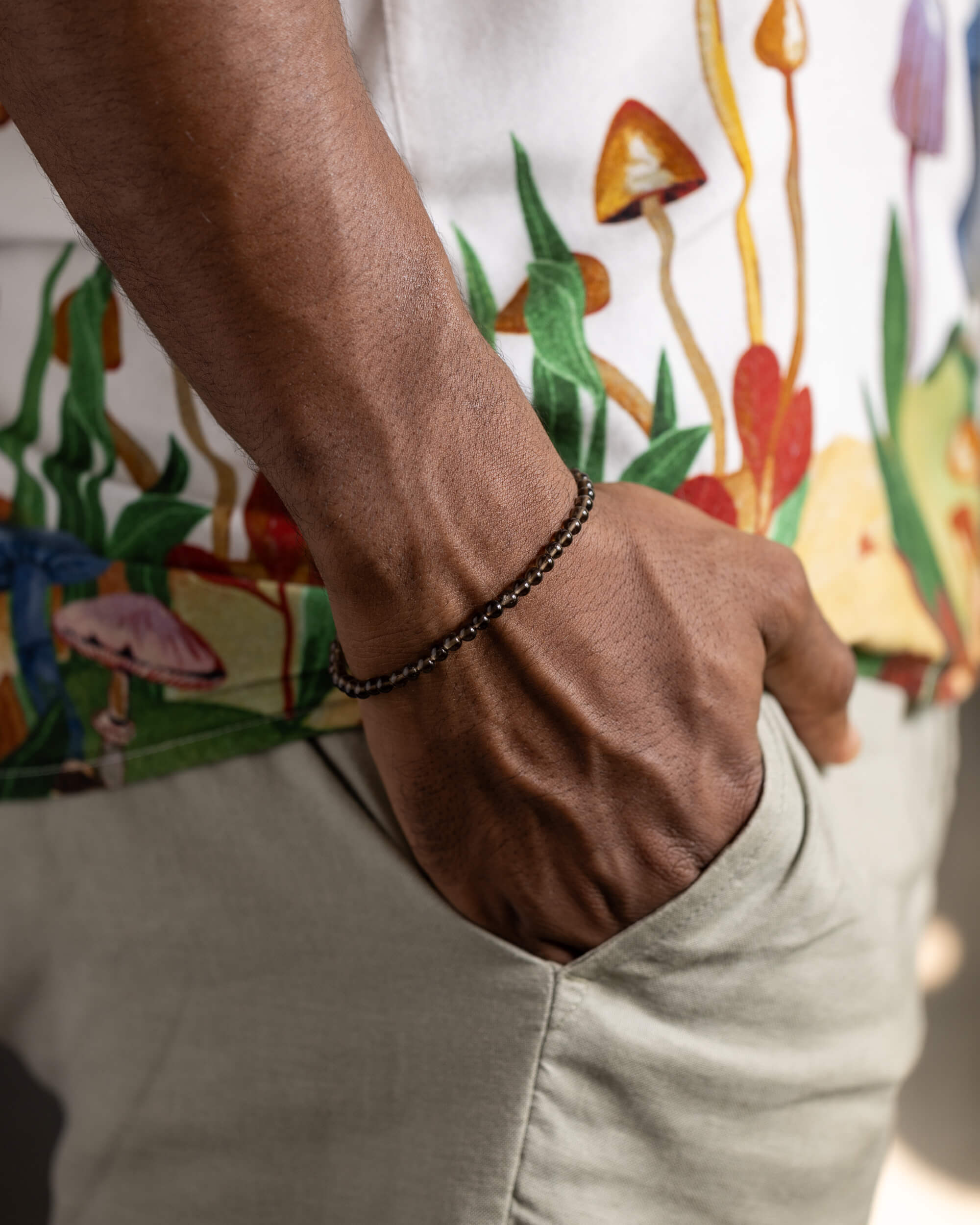 Pulsera de Cuarzo Ahumado puesta en la muñeca, con camisa estampada de hongos