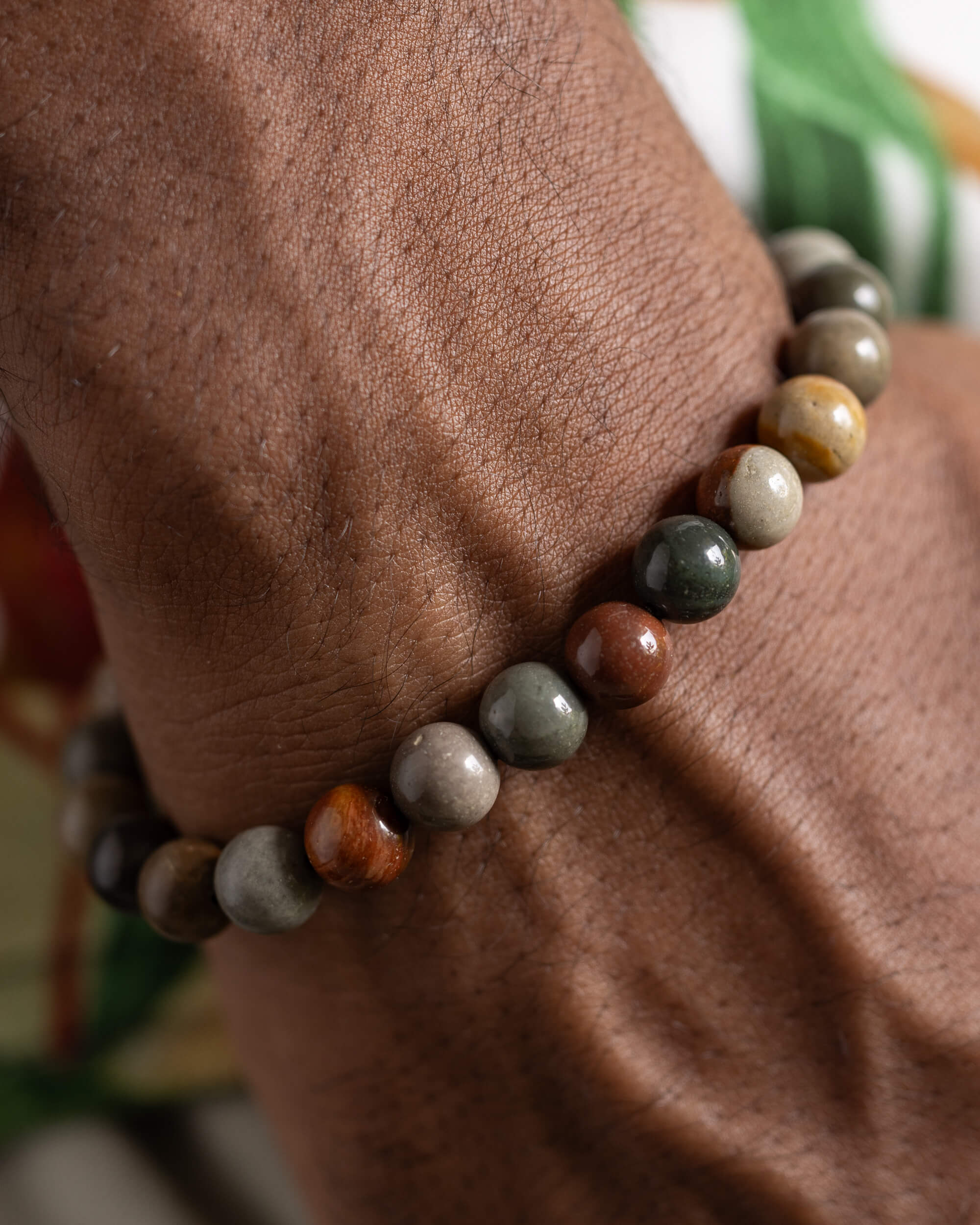 Pulsera de Madera Petrificada puesta en la muñeca con vegetación al fondo