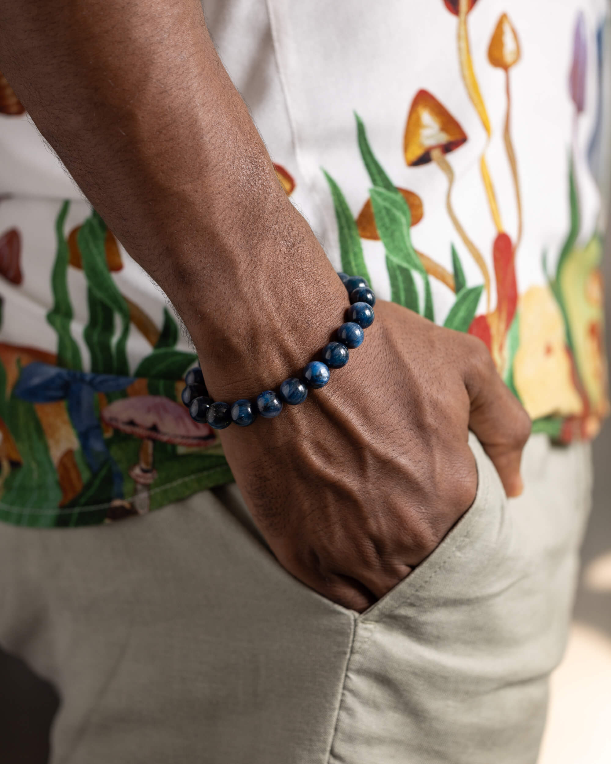 Pulsera de Cianita Azul puesta en la muñeca, con camisa estampada de hongos