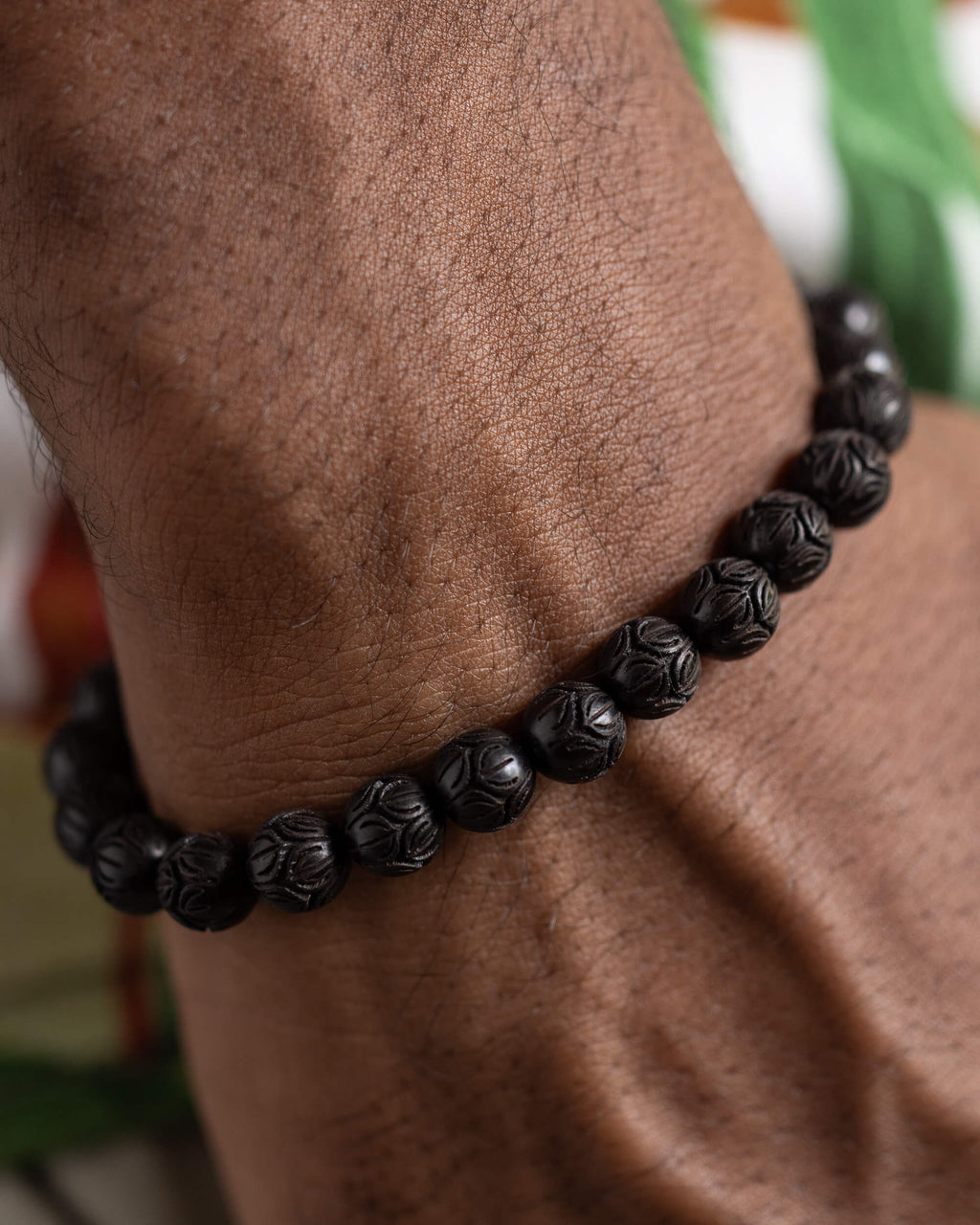 Pulsera de Madera de Ebano tallada con flor de loto puesta, vista cercana en la muñeca