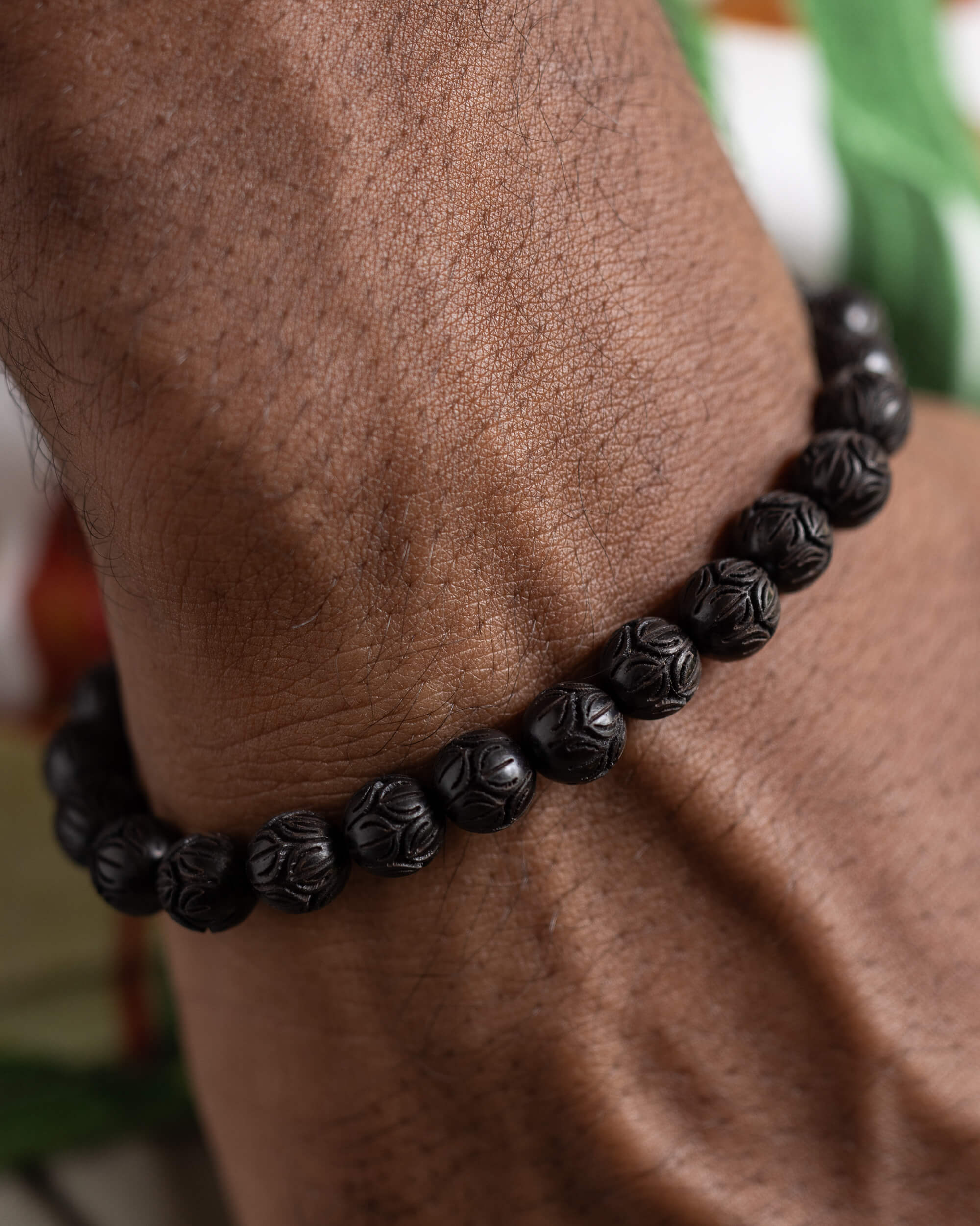 Pulsera de Madera de Ebano tallada con flor de loto puesta, vista cercana en la muñeca