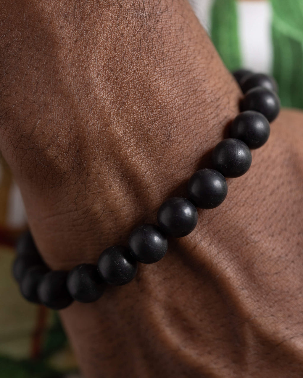 Pulsera de Shungita puesta en la muñeca, detalle cercano de las cuentas negras