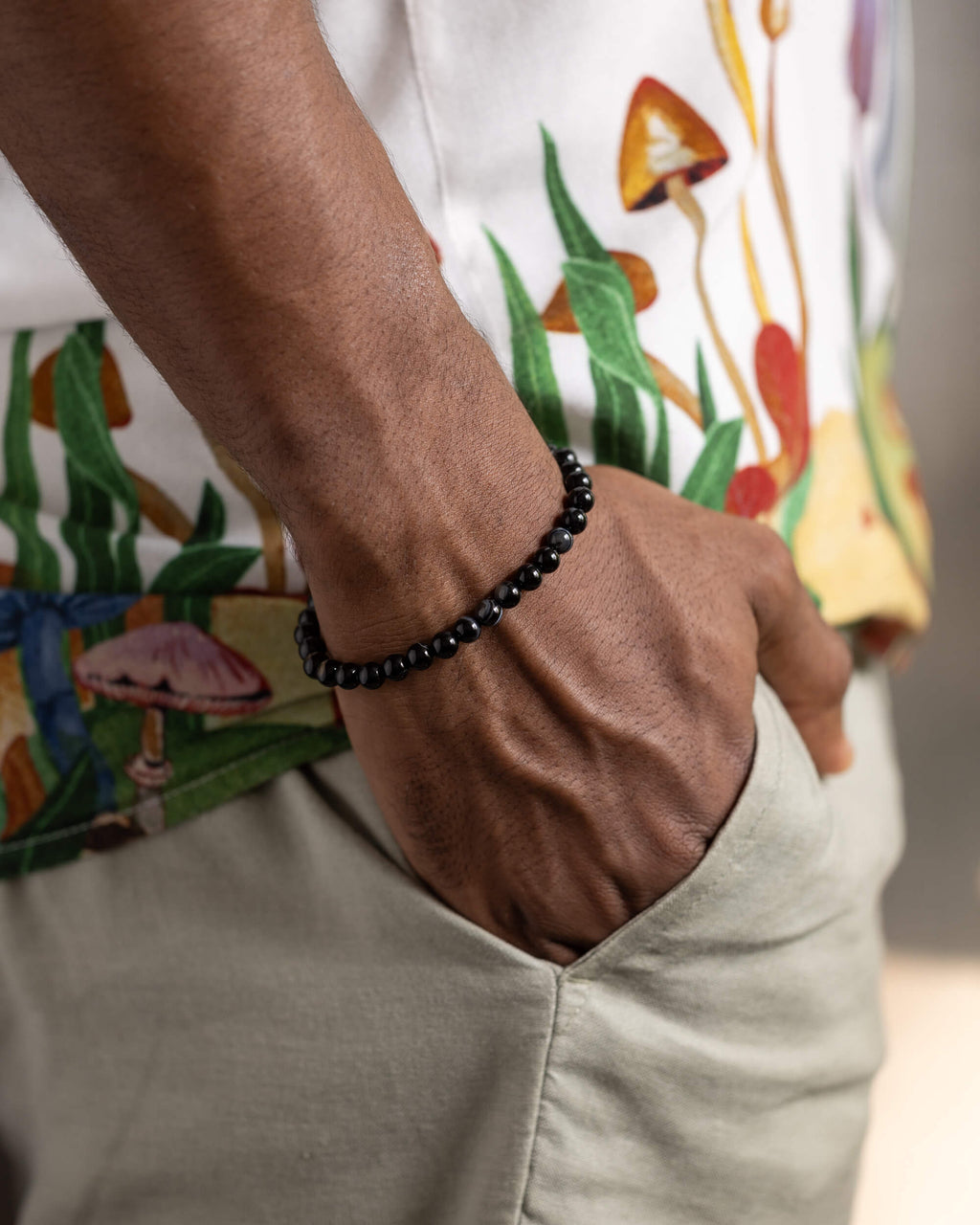 Pulsera de Ágata Negra puesta en la muñeca, con camisa estampada de hongos