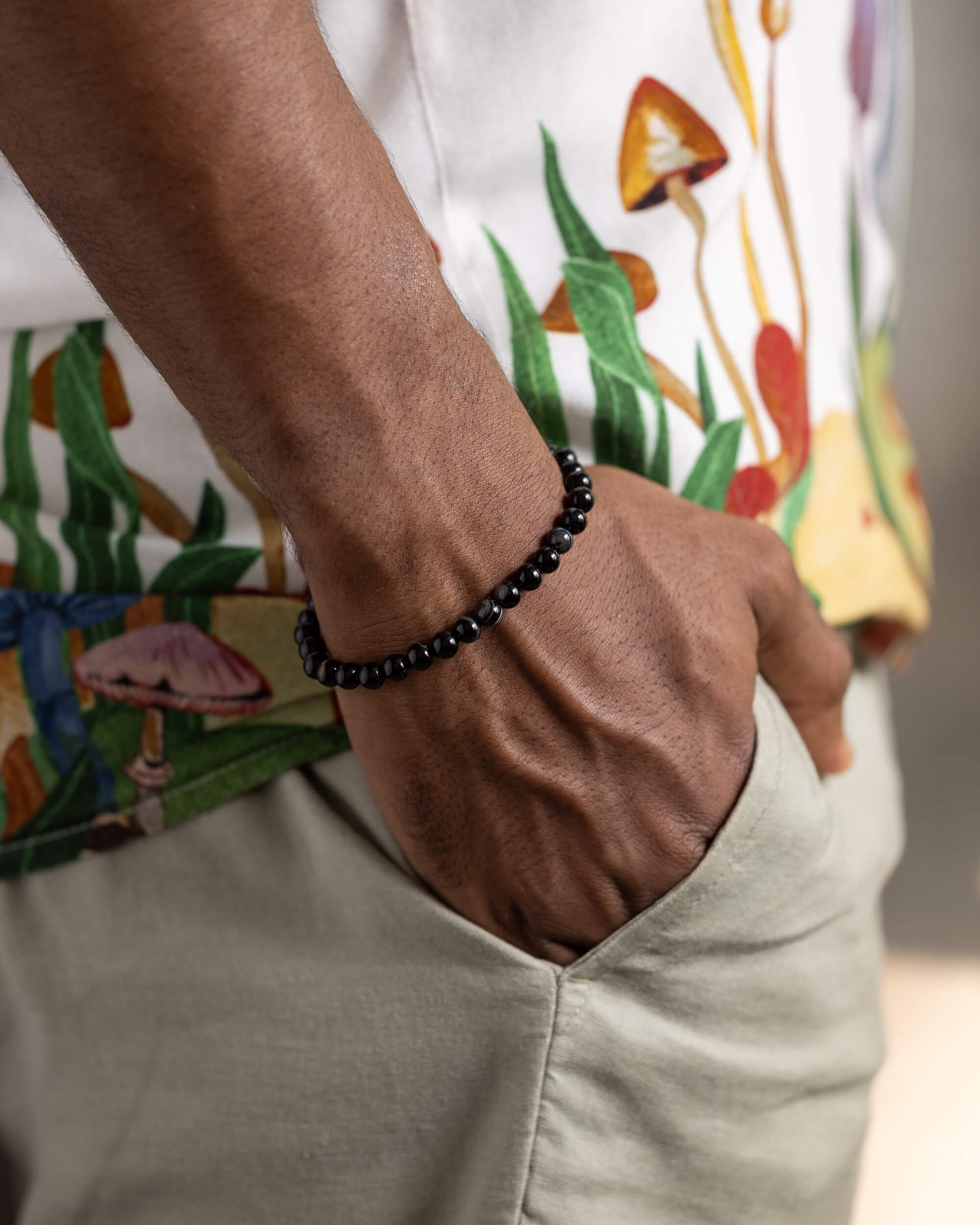 Pulsera de Ágata Negra puesta en la muñeca, con camisa estampada de hongos