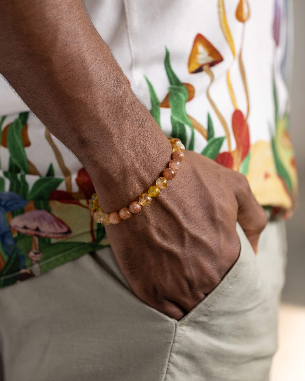 Pulsera Sol Invictus puesta en la muñeca, mano en el bolsillo de un pantalón claro