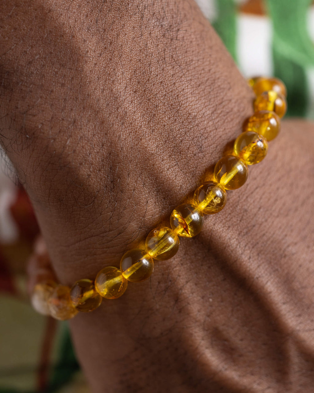 Pulsera Sol Invictus puesta en la muñeca, cuentas de Ámbar cerca de la mano