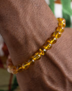 Pulsera Sol Invictus puesta en la muñeca, cuentas de Ámbar cerca de la mano